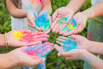 A picture in which there are couple of hands holding holi colours